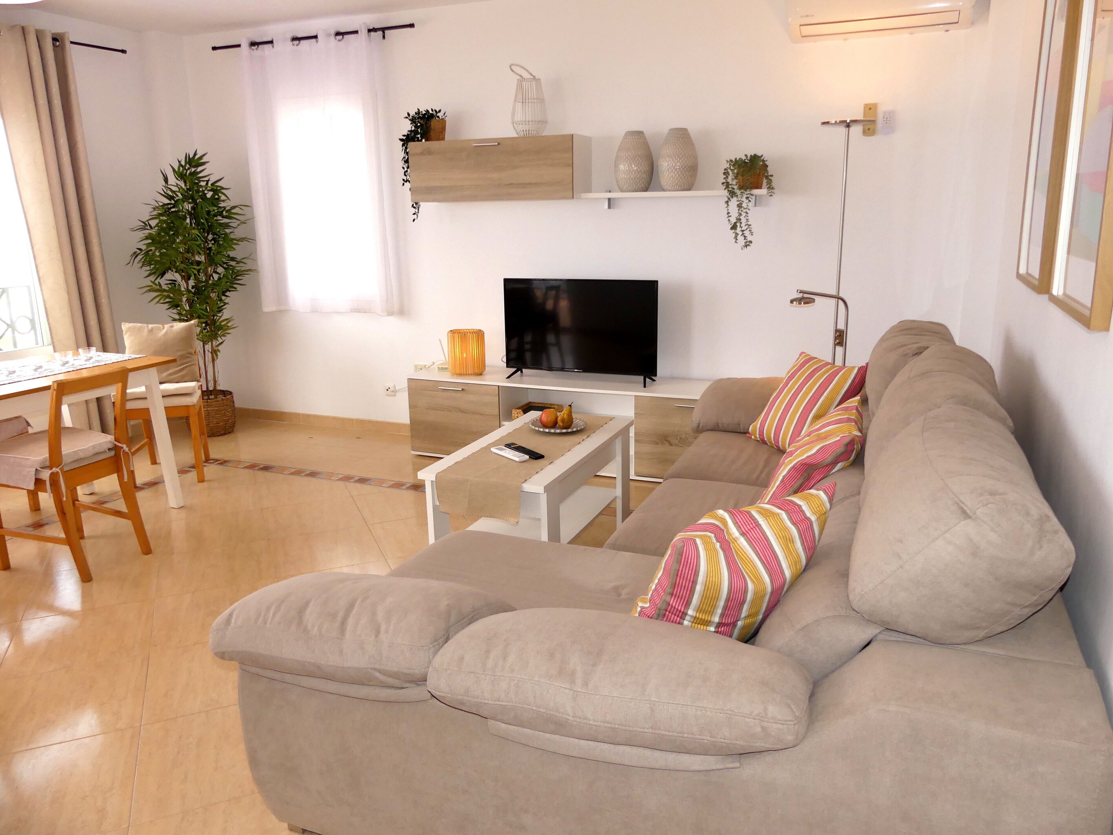 Un salon moderne comprenant un canapé, un téléviseur et un coin repas avec une table et des chaises.