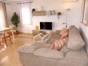 A modern living room with a sofa, TV, and a dining area with a table and chairs. - Holiday Home 'Villa Brisas Del Mar' with Sea View, Wi-Fi and Air Conditioning (Torrox)