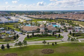 A residential area with a large house featuring a swimming pool, surrounded by parked cars and lush greenery. - Upstay: Family Home w Pool & Cinema—ChampionsGate (Davenport)