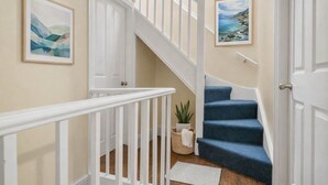 A staircase with white railings and blue carpeted steps leading to a door. - 4BR Home Perfect for Professionals (Beeston)