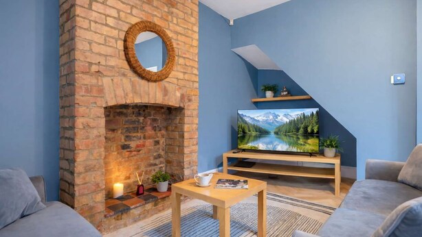 A cozy living room with a brick fireplace, a flat-screen TV, and comfortable seating. - 4BR Home Perfect for Professionals (Beeston)