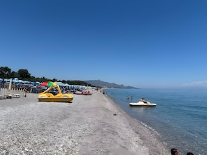 Ein Strand mit Booten, Sonnenschirmen und blauem Himmel.