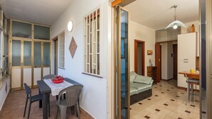 A room with a dining table, chairs, a bed, and a sliding door leading to another room. - Angelina's House Apartment with Balcony and Air Conditioning (Sant'Anna)