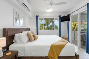 Ein Hotelzimmer mit einem Bett, einem Deckenventilator, einem Fernseher und einem Fenster mit Vorhängen.
