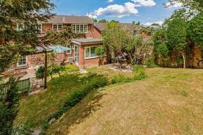 A residential property with a brick house, a covered patio, and a grassy yard. - Hillside House in Henley (Oxfordshire)
