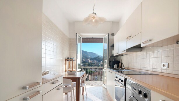 Eine moderne Küche mit integriertem Waschmaschine, ein Essbereich mit Blick und ein Balkon mit Bergblick.