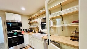 Una cocina moderna con armarios blancos, electrodomésticos de acero inoxidable y estantes de madera.