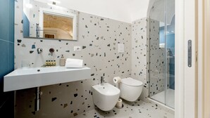 Un baño moderno con lavamanos, bidé, inodoro y cabina de ducha con mampara de vidrio.