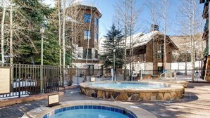 A pool area with two hot tubs, surrounded by a brick walkway and a metal fence. - Charming 2-bedroom 2- Bathroom Ski in/out apartment in Beaver Creek. (Beaver Creek)