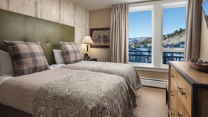 A hotel room with two beds, a nightstand, a lamp, a painting, and a view of a landscape through a window. - Charming 2-bedroom 2- Bathroom Ski in/out apartment in Beaver Creek. (Beaver Creek)