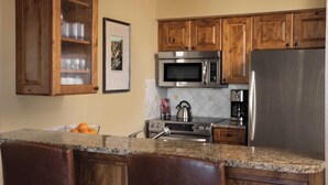 A kitchen with wooden cabinets, a stainless steel refrigerator, a microwave, and an oven. - Charming 2-bedroom 2- Bathroom Ski in/out apartment in Beaver Creek. (Beaver Creek)
