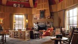 A cozy, wood-paneled living room with a fireplace, comfortable seating, and large windows offering views. - Charming 2-bedroom 2- Bathroom Ski in/out apartment in Beaver Creek. (Beaver Creek)