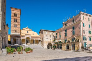 A historic square with a prominent tower, a church with a dome, and traditional buildings with balconies and windows. - Villa Fortunata (Terracina)