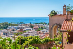 A coastal town with terracotta-roofed buildings, a prominent archway, and a view of the sea. - Villa Fortunata (Terracina)