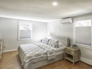 Ein Schlafzimmer mit Bett, Nachttisch und zwei Fenstern.
