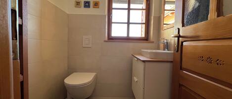 Une petite salle de bain avec des toilettes, un lavabo et une fenêtre.