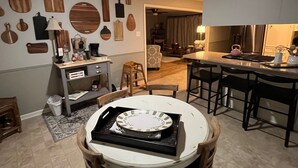 Un espace repas avec une table ronde, des chaises et une cuisine en arrière-plan.