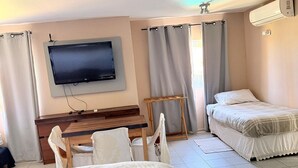 Una habitación de hotel con dos camas, un televisor montado en la pared, un escritorio y una silla.
