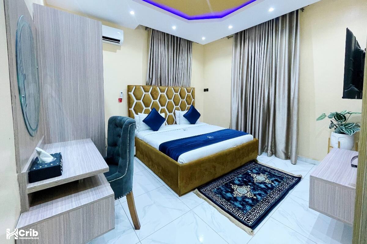 A modern bedroom with a bed, a desk, a chair, and a large mirror.