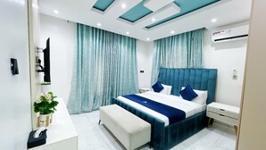 A modern bedroom with a large bed, a bedside table, a bench, and a small desk. - Alubarika Service Apartments (Lagos)