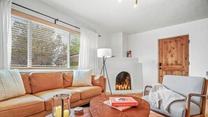 A living room with a sofa, armchair, coffee table, and a fireplace. - Private Santa Fe Retreat Near Plaza · Fire Pit · 3 King Bedrooms (Santa Fe)