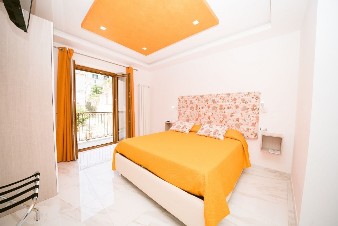 A modern bedroom with a large bed, a view of the outside, and a small bedside table.
