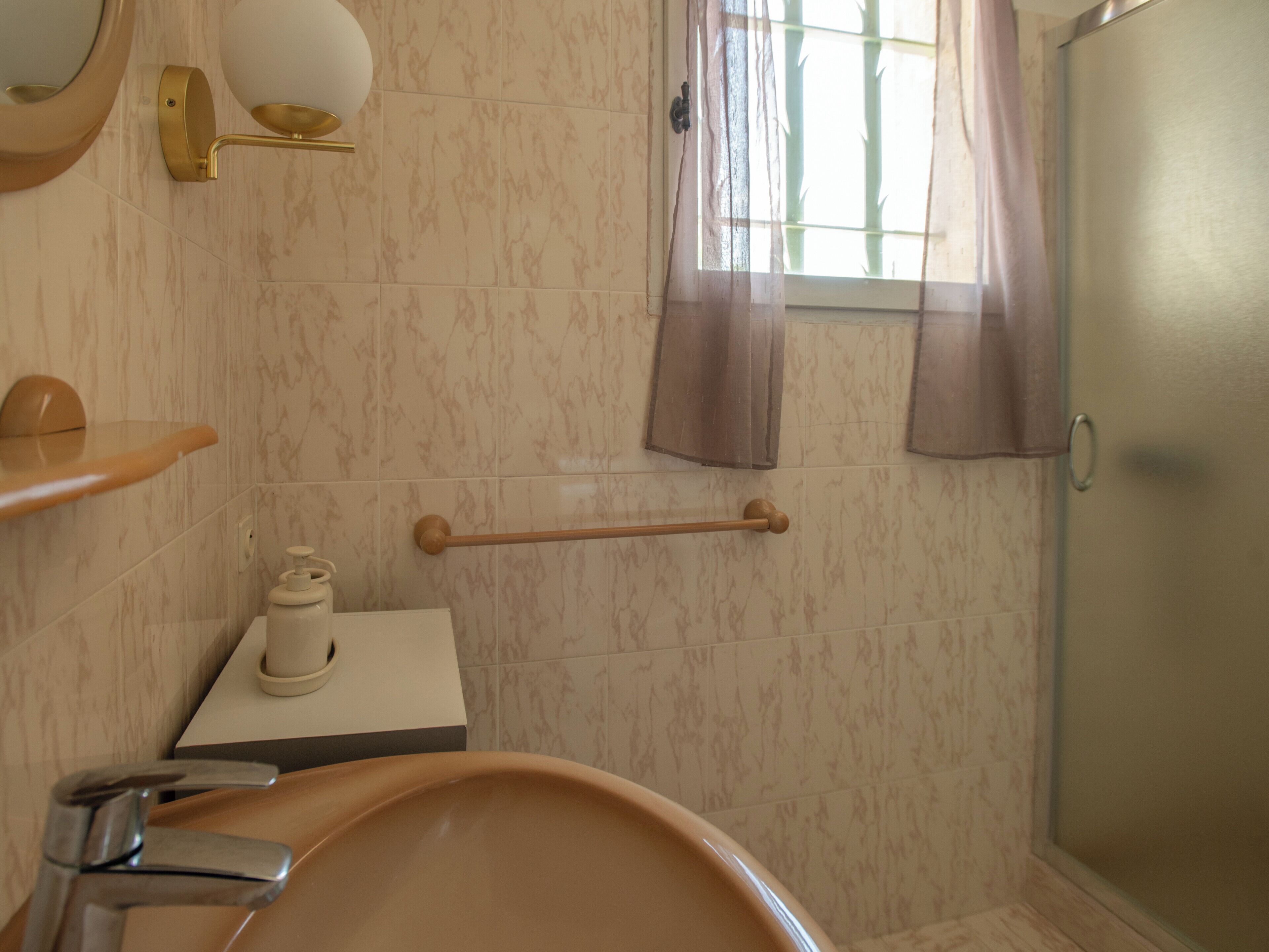 Un baño con bañera, inodoro, lavabo, espejo, toallero y ventana con cortinas.