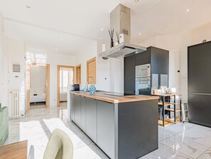 A modern kitchen with a central island, built-in appliances, and a dining area with a table and chairs. - Bail mobilité - Appartement 2 ch - Nice centre (Nice)