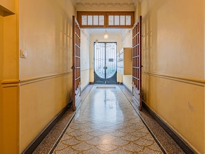 A hallway with a tiled floor leading to a double door with a decorative metal design. - Bail mobilité - Appartement 2 ch - Nice centre (Nice)