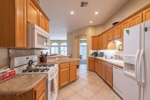 A modern kitchen with wooden cabinets, a gas stove, a microwave, a refrigerator, and a dishwasher.