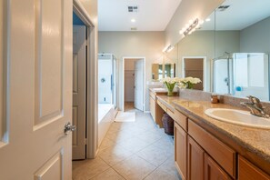 A modern bathroom with a large mirror, a sink, and a shower.