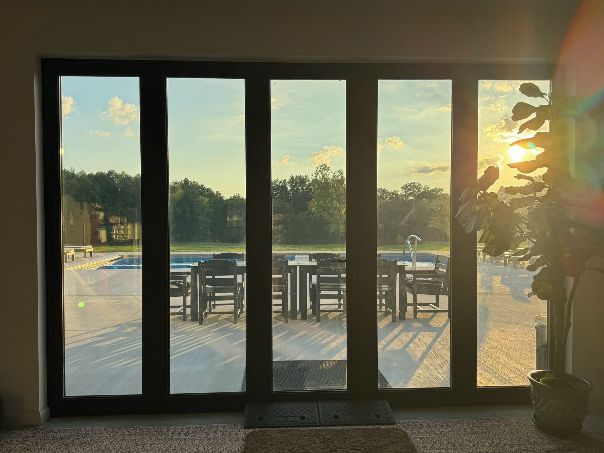 A room with large windows overlooking an outdoor seating area with tables and chairs.