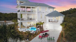 Ein zweistöckiges Haus mit großem Balkon, Schwimmbecken und einer überdachten Terrasse.