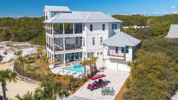 Ein mehrstöckiges Haus mit Pool, umgeben von Palmen und einem Strand.