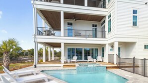 Ein zweistöckiges Haus mit Schwimmbad, Außenbereich und überdachter Terrasse.