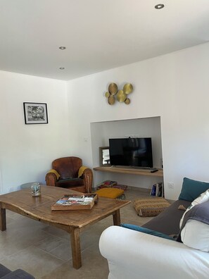 A living room with a television, a brown leather armchair, a white sofa, a wooden coffee table, and a decorative wall piece. - Charming family home in the heart of Périgord Noir, between Lascaux and Sarlat. (La Chapelle-Aubareil)