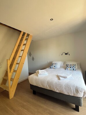 A bedroom with a bed, pillows, a wooden ladder, and a wall-mounted light fixture. - Charming family home in the heart of Périgord Noir, between Lascaux and Sarlat. (La Chapelle-Aubareil)