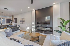 A modern living room with a sofa set, a coffee table, and a flat-screen TV mounted on a wall. - 12 Rooms, 12 baths, 3 Townhomes. 2mi to Broadway (Nashville)