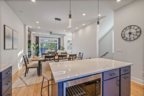 A modern kitchen with a central island, pendant lights, and a clock on the wall. - 12 Rooms, 12 baths, 3 Townhomes. 2mi to Broadway (Nashville)