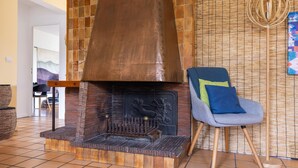 Un salon moderne avec une cheminée en briques, un fauteuil confortable et un élément décoratif mural.