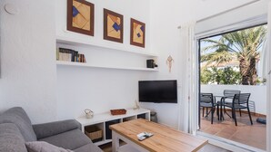 A living room with a sofa, a coffee table, a TV, and a bookshelf. - Holiday Home 'Denia Encantadora' with Shared Pool, Wi-Fi and Air Conditioning (DENIA)