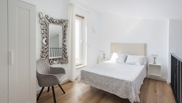 A bedroom with a bed, a chair, a dresser, a mirror, and a nightstand. - Holiday Home 'Denia Encantadora' with Shared Pool, Wi-Fi and Air Conditioning (DENIA)