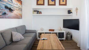 A living room with a grey sofa, a wooden coffee table, a white TV stand, and a painting on the wall. - Holiday Home 'Denia Encantadora' with Shared Pool, Wi-Fi and Air Conditioning (DENIA)