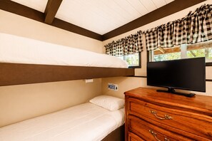 Ein Schlafzimmer mit Etagenbett und einem Fernseher auf einer Holzkommode.