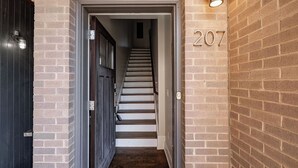 Una escalera estrecha que lleva a una puerta con el número 207 en la pared.