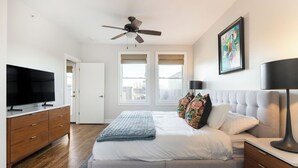 Un dormitorio con una cama, un ventilador de techo, un televisor y un cuadro en la pared.