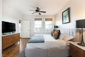 A bedroom with a bed, a ceiling fan, a TV, and a painting on the wall. - 12 South Townhome across from Sevier Park (Nashville)