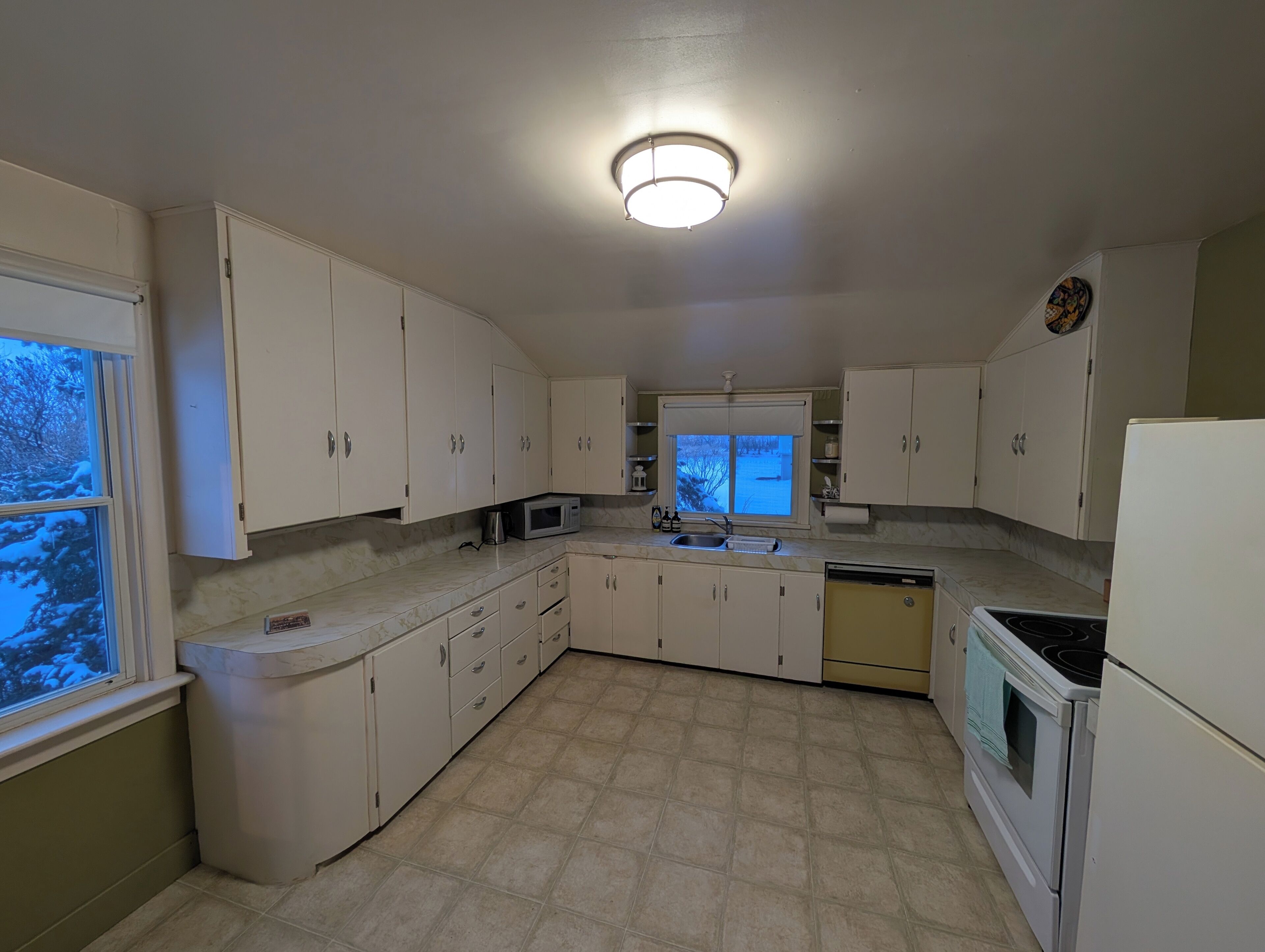 A kitchen with white cabinets, a microwave, a sink, and a stove.