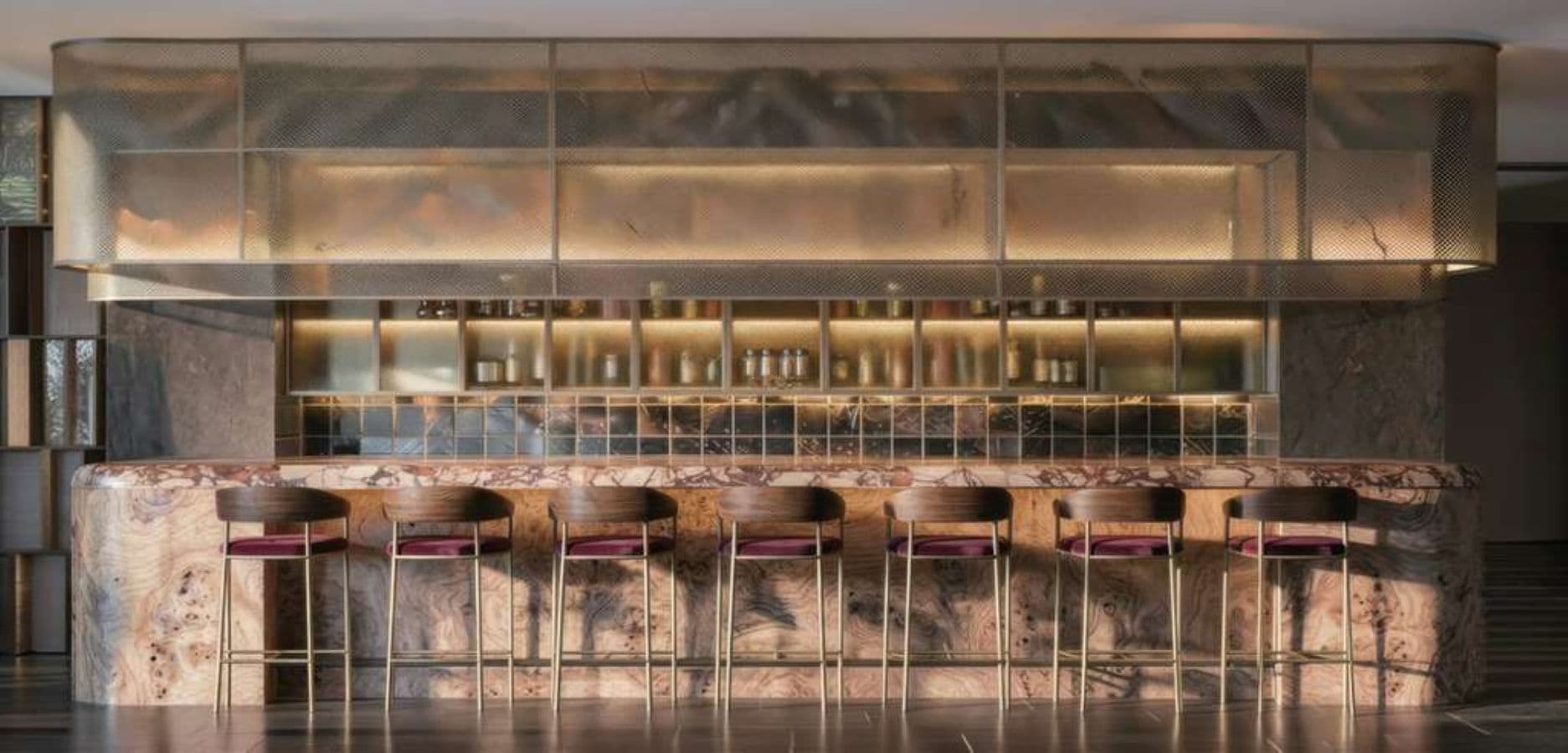 A bar area with a marble countertop and stools.