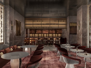 A modern lounge area with a sofa, ottomans, a coffee table, and potted plants. at Hotel Clark